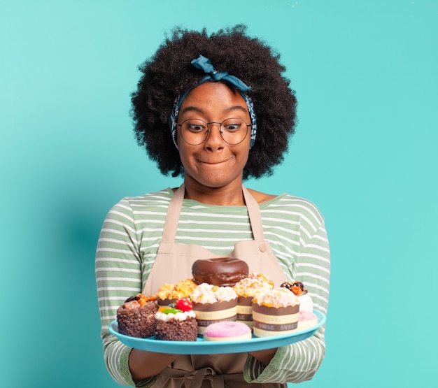 Panadero joven bonita mujer afro con tortas