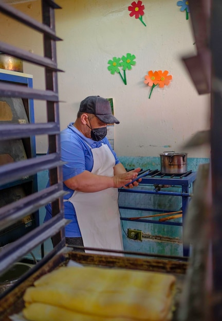 Panadero latino con máscara trabajando en una panadería y pastelería tradicional mexicana.