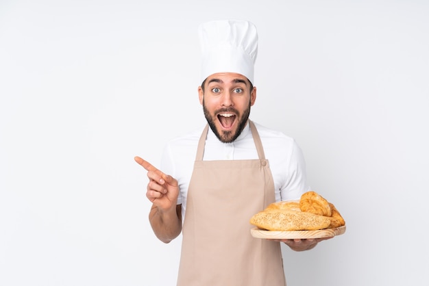 Panadero masculino sosteniendo una mesa con varios panes aislados