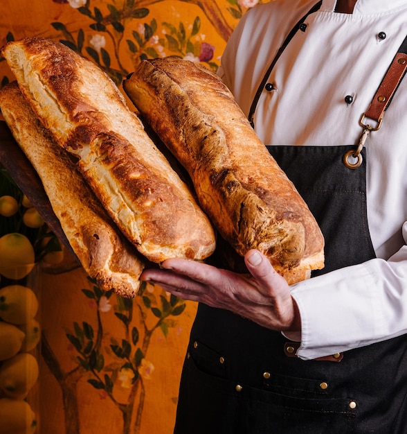 El panadero presenta baguettes recién horneadas