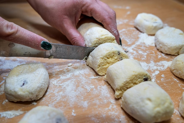 Panadero profesional con cuchillo corta la masa de salchicha cruda incluso en trozos pequeños