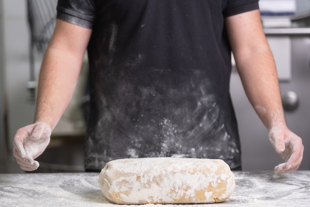 Panadero que amasa la masa fresca del pan crudo en la panadería.