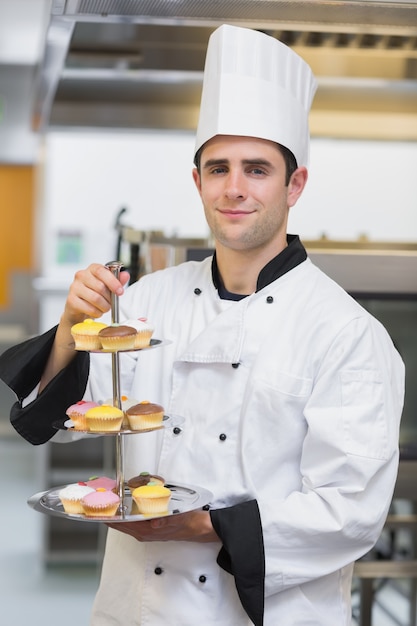 Foto panadero sosteniendo bandeja de pastel escalonado