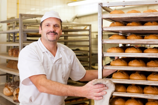 Foto panadero en su panadería horneando pan