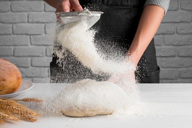 Panadero tamizando la harina sobre la masa