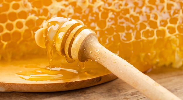 panal dulce con miel de abeja con una cuchara de madera en un plato