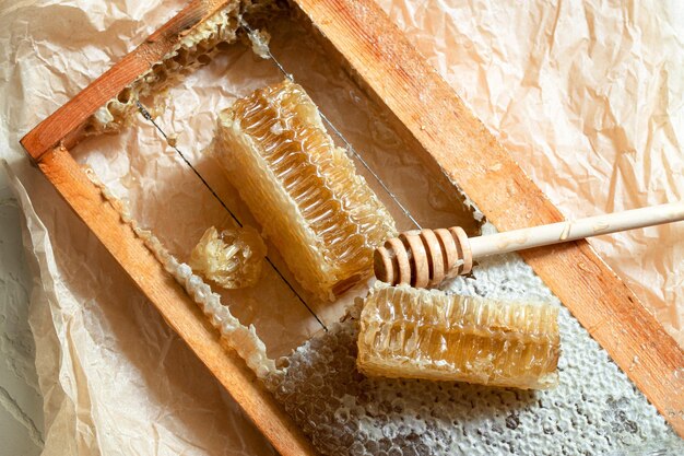 Panal de miel sellado en un marco de madera con cucharón de madera para mezclar y degustar miel natural ...
