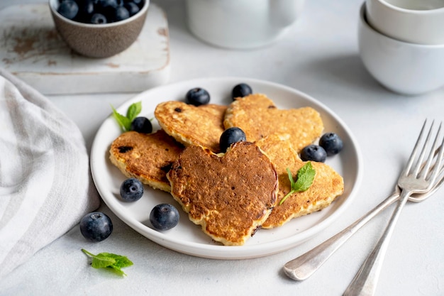 Pancakesheart moldado com mirtilos frescos Café da manhã deliciosos panquecas veganas Fundo brilhante