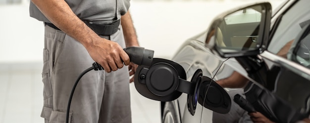 La pancarta de closeup asian technician hand está cargando el automóvil eléctrico o ev en el centro de servicio para su mantenimiento, concepto de energía alternativa ecológica, portada y pancartas