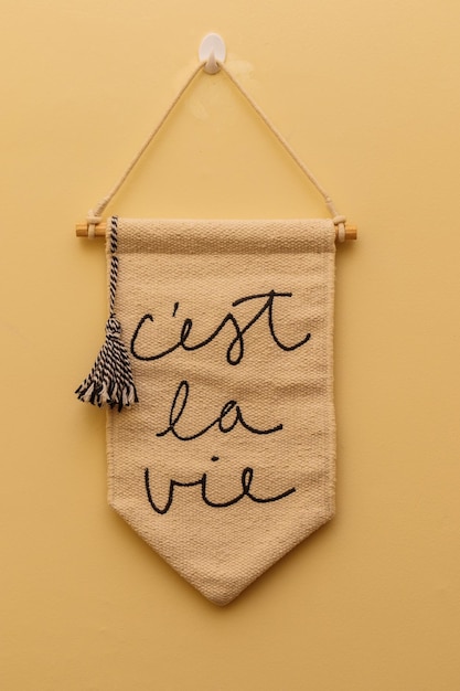 pancarta decorativa escrita en francés c'est la vie en una pared de fondo amarillo