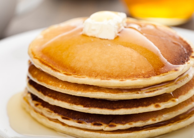 Panckes con mantequilla y almíbar con café de fondo