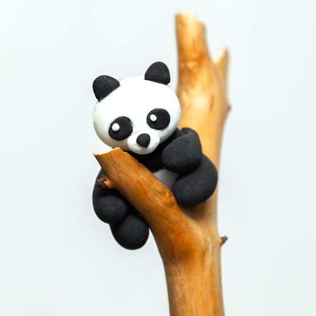 Panda de plasticina pendura em um galho