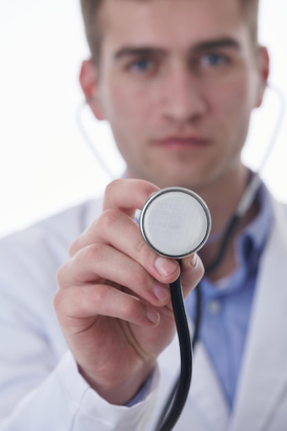 Pandemia de coronavirus covid-19 Retrato de héroe en bata blanca. Alegre joven médico sonriente con estetoscopio en el hospital médico de pie contra el fondo blanco.