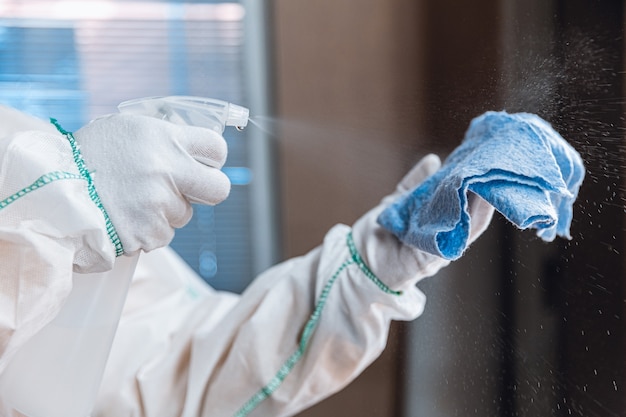 Foto pandemia de coronavirus. un desinfectante con traje protector y mascarilla rocía desinfectantes en casa u oficina. protección contra la enfermedad covid-19. prevención de la propagación del virus de la neumonía con superficies.