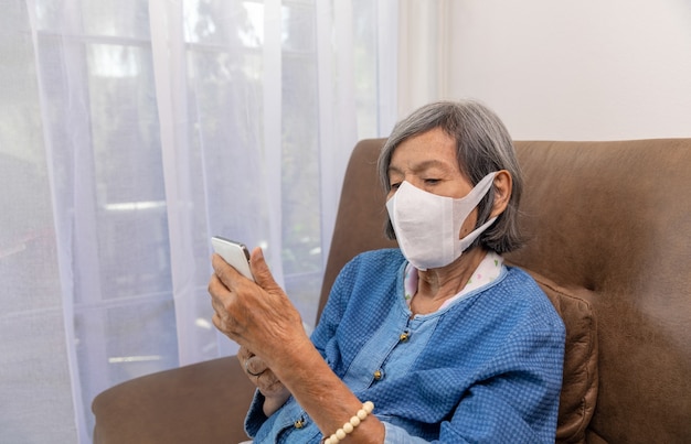 Pandemia de Covid19 Mulher idosa relaxando na sala de estar navegando na Internet sem fio no celular