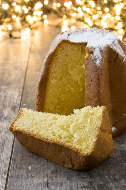 Pandoro Christmas cake con azúcar en mesa de madera y luz de navidad