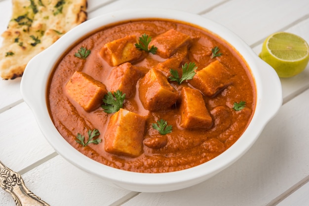 Paneer Butter Masala o Cheese Cottage Curry, popular menú indio de almuerzo y cena servido en Karahi con Naan o Roti sobre fondo cambiante, enfoque selectivo