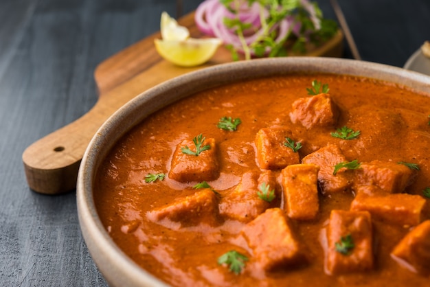 Paneer Butter Masala o Cheese Cottage Curry, popular menú indio de almuerzo y cena servido en Karahi con Naan o Roti sobre fondo cambiante, enfoque selectivo