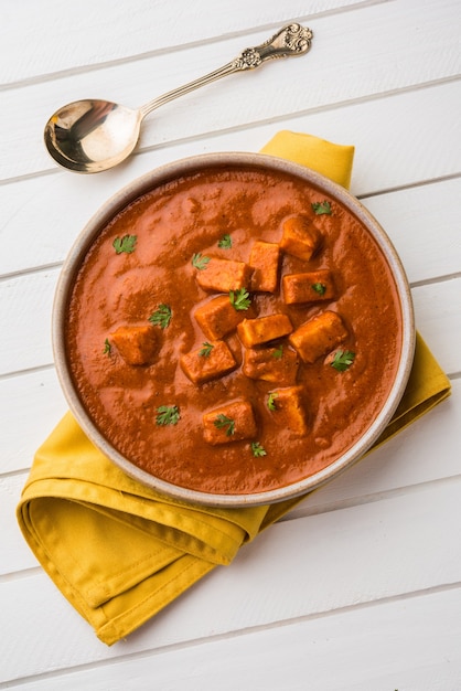 Paneer Butter Masala o Cheese Cottage Curry, popular menú indio de almuerzo y cena servido en Karahi con Naan o Roti sobre fondo cambiante, enfoque selectivo