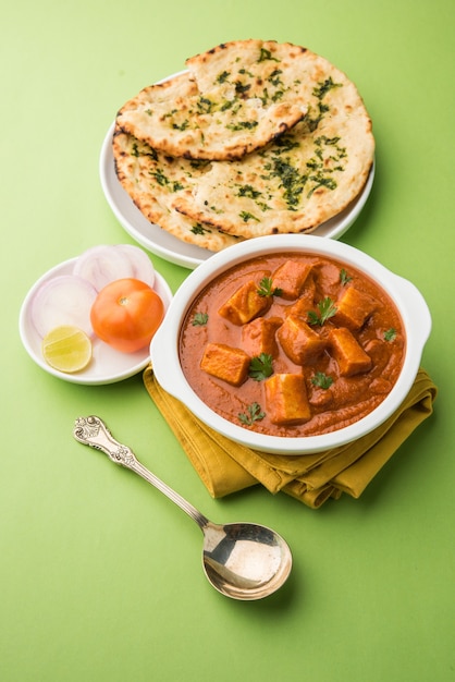 Paneer Butter Masala ou Cheese Cottage Curry, menu de almoço e jantar indiano popular servido em Karahi com Naan Or Roti sobre fundo sombrio, foco seletivo