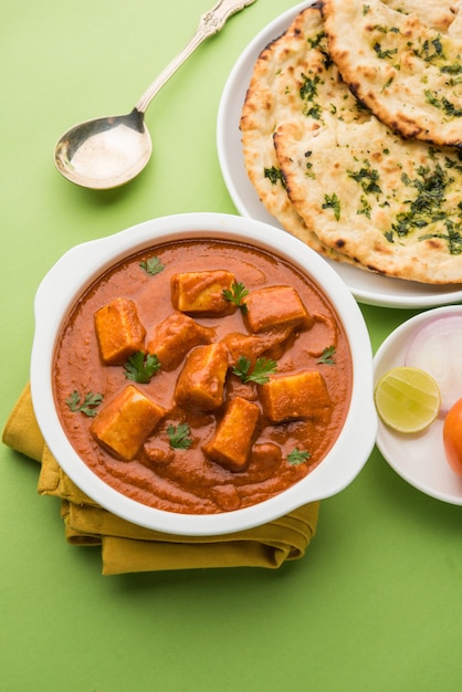 Paneer Butter Masala ou Cheese Cottage Curry, menu de almoço e jantar indiano popular servido em Karahi com Naan Or Roti sobre fundo sombrio, foco seletivo