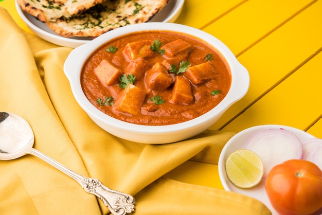 Paneer Butter Masala ou Cheese Cottage Curry, menu de almoço e jantar indiano popular servido em Karahi com Naan Or Roti sobre fundo sombrio, foco seletivo