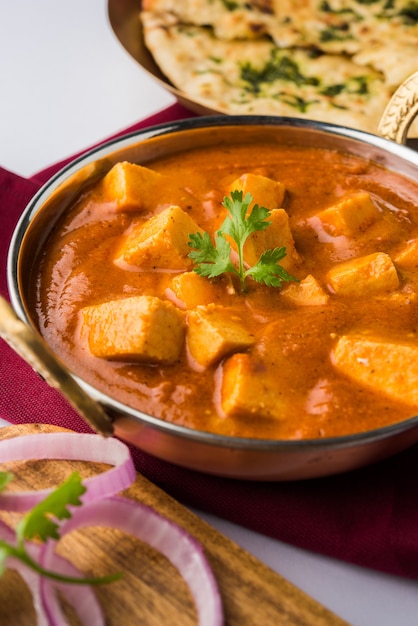 Paneer Butter Masala ou Cheese Cottage Curry, menu de almoço e jantar indiano popular servido em Karahi com Naan Or Roti sobre fundo sombrio, foco seletivo