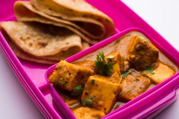 Paneer Butter Masala con Roti en lonchera o tiffin, enfoque selectivo