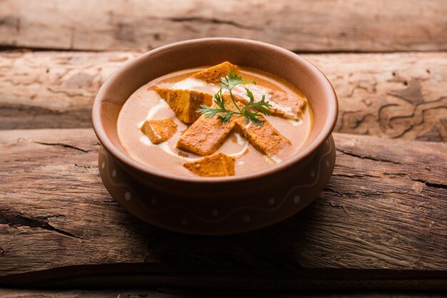 Paneer Butter Masala também conhecido como Panir makhani ou makhanwala. servido em uma tigela de cerâmica ou terracota com creme fresco e coentro.