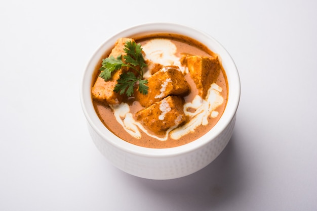 Paneer Butter Masala também conhecido como Panir makhani ou makhanwala. servido em uma tigela de cerâmica ou terracota com creme fresco e coentro.