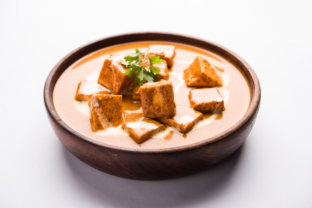 Paneer Butter Masala também conhecido como Panir makhani ou makhanwala. servido em uma tigela de cerâmica ou terracota com creme fresco e coentro.