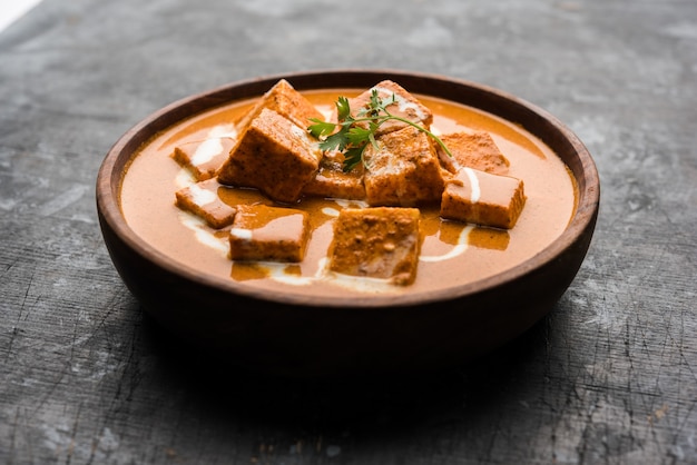 Paneer Butter Masala também conhecido como Panir makhani ou makhanwala. servido em uma tigela de cerâmica ou terracota com creme fresco e coentro.