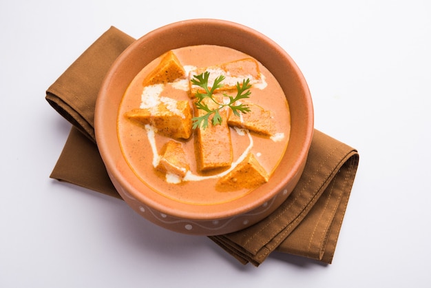 Paneer Butter Masala también conocido como Panir makhani o makhanwala. servido en un cuenco de cerámica o terracota con crema fresca y cilantro el enfoque selectivo.