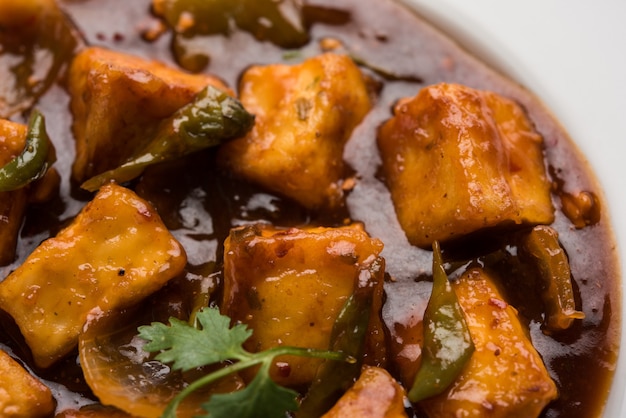 Paneer de chile o requesón picante, servido en un plato blanco con pimiento y cebolla, menú de entrada indio favorito, enfoque selectivo