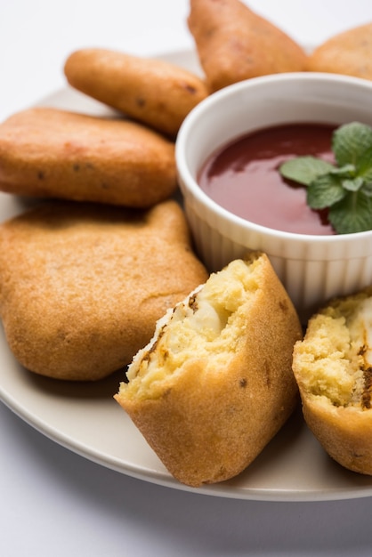 Paneer pakoras o Bhajji son cubos de requesón picante recubiertos de harina de garbanzos o masa de besan. Servido con salsa de tomate en un plato sobre fondo de colores o madera. Enfoque selectivo