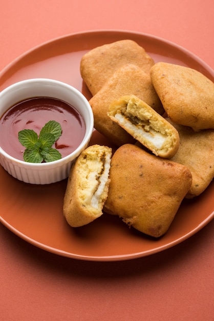 Paneer Pakoras oder Bhajji sind mit Grammmehl oder Besan-Teig überzogene würzige Hüttenkäsewürfel. Serviert mit Tomatenketchup in einem Teller über buntem oder hölzernem Hintergrund. Selektiver Fokus