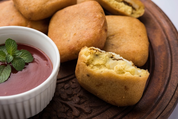 Paneer Pakoras oder Bhajji sind mit Grammmehl oder Besan-Teig überzogene würzige Hüttenkäsewürfel. Serviert mit Tomatenketchup in einem Teller über buntem oder hölzernem Hintergrund. Selektiver Fokus