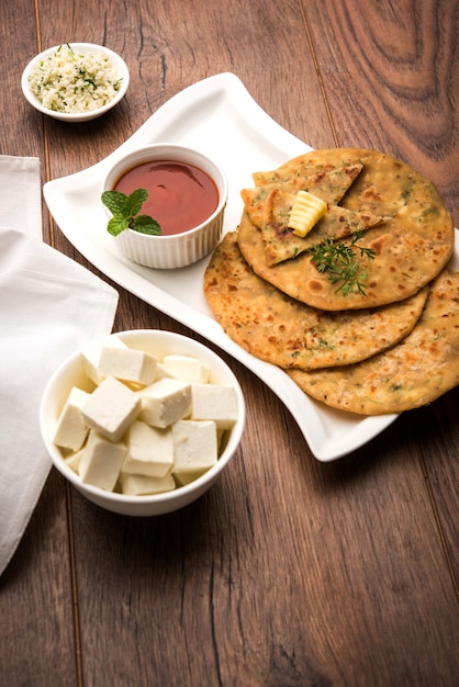 Paneer Paratha gefüllt mit schmelzender Butter, serviert mit frischen Hüttenkäsewürfeln und Tomatenketchup. Selektiver Fokus