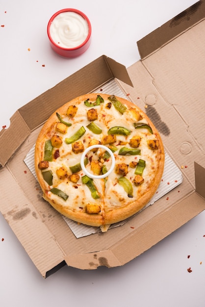 Paneer Pizza ist eine indische Version eines italienischen Gerichts mit Hüttenkäse, serviert auf einem Teller mit weißer Soße. selektiver Fokus