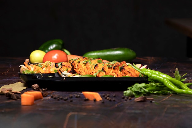 Paneer tikka é um prato indiano feito de pedaços de paneer com molho e legumes na mesa