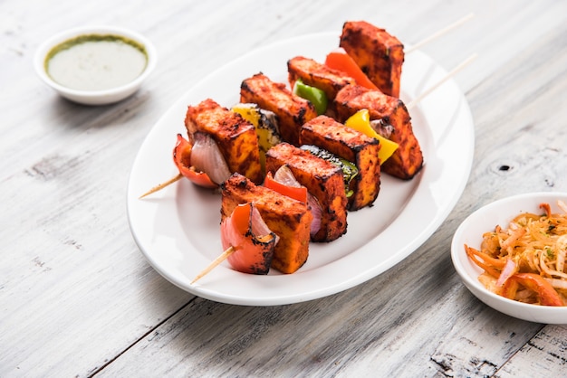 Paneer Tikka Kabab en salsa roja es un plato indio hecho con trozos de requesón