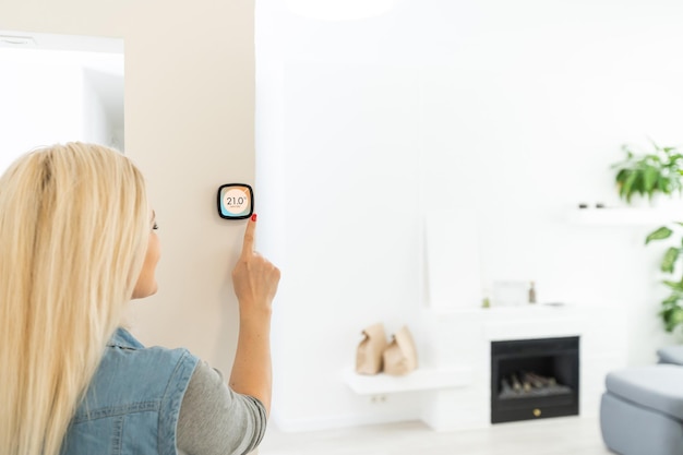 Panel de control domótico del hogar inteligente del termostato en la pared para pancarta panorámica de temperatura de la casa de invierno. Mano de ahorro de energía tocando para ajustar la temperatura de calefacción en la sala de estar.