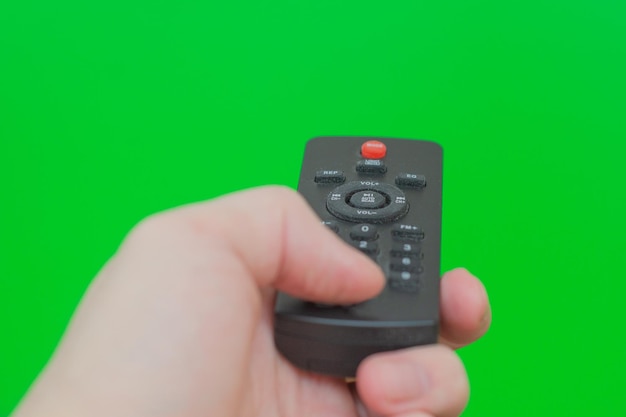 Foto el panel de control del televisor en una mano masculina sobre un fondo verde
