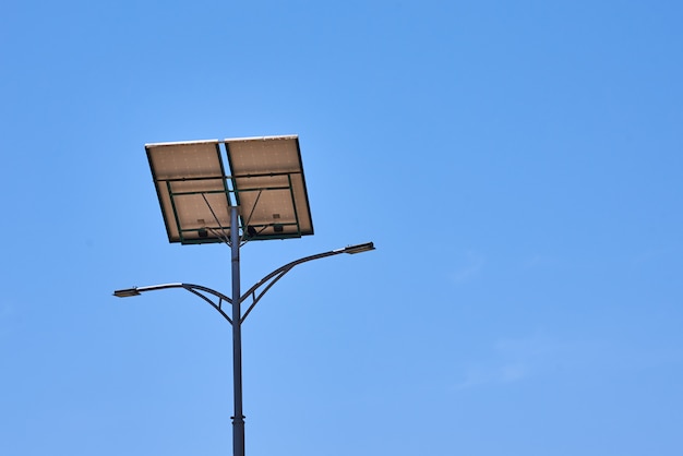 El panel solar en el cielo azul del aganst de la lámpara de calle. Energía alternativa del concepto solar.