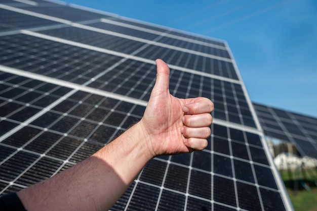 El panel solar en el techo produce electricidad en el fondo de una mano con un dedo hacia arriba