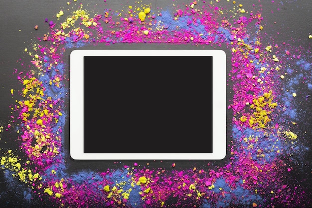 Panel táctil sobre fondo colorido de polvo holi Computadora con pantalla táctil sobre fondo de colores festivos holi