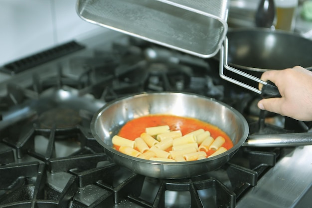 panela com macarrão no fogo fogão cozinhando