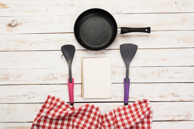 Panela de ferro fundido e outros utensílios de cozinha na mesa de madeira, vista superior