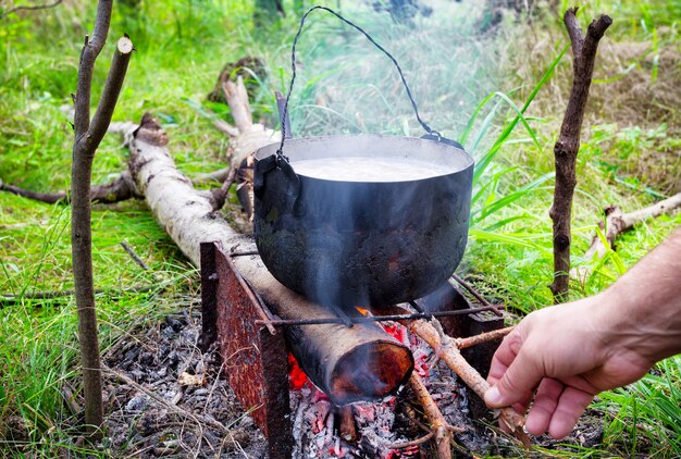 Panela no fogo com lenha lança mão