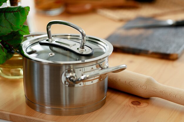 Panela pequena de alumínio na mesa de madeira da cozinha